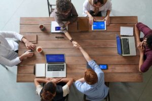 meeting around a table with laptops and shaking hands