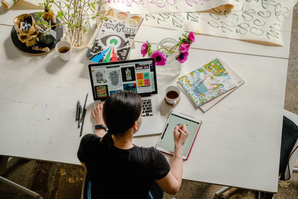 aerial shot of lady writing on iPad at desk